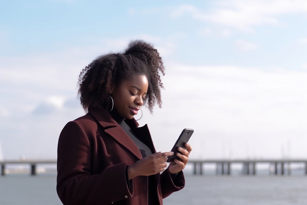 Black woman with cell phone standing at the waterfront travel adult photo. AI generated Image by rawpixel.