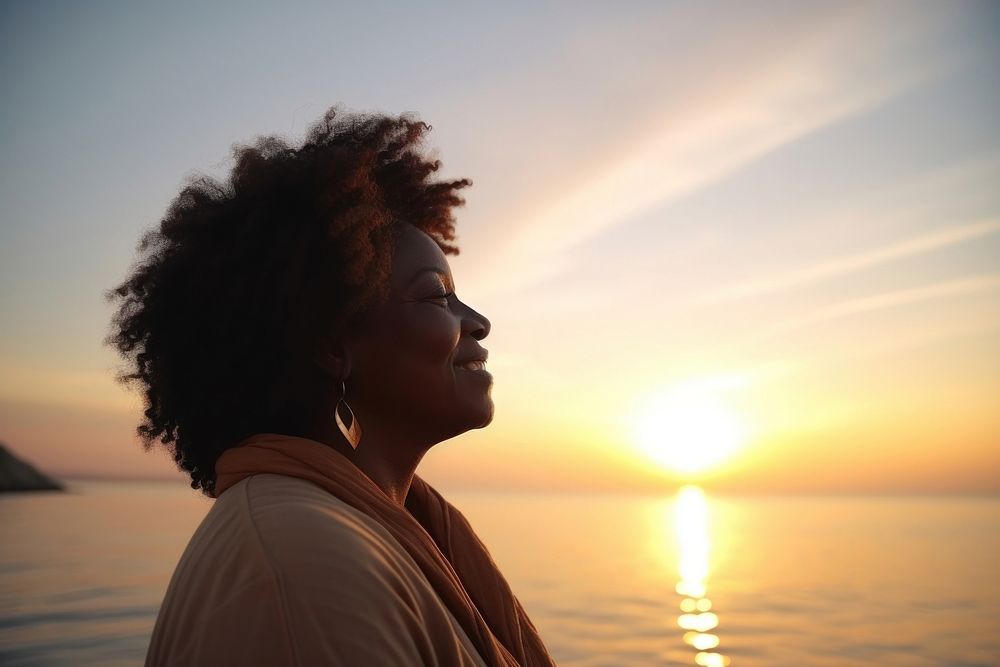 Black mature woman enjoying sunset by the sea portrait outdoors nature. AI generated Image by rawpixel.