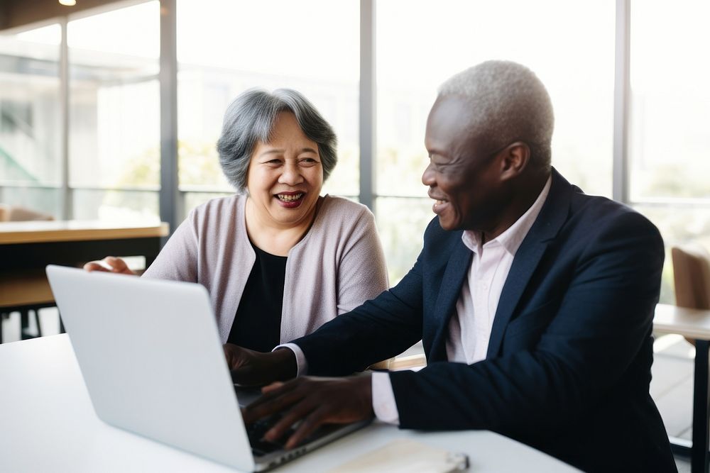 Happy senior old korean businesswoman discussing online project on laptop with african american male computer adult happy.…