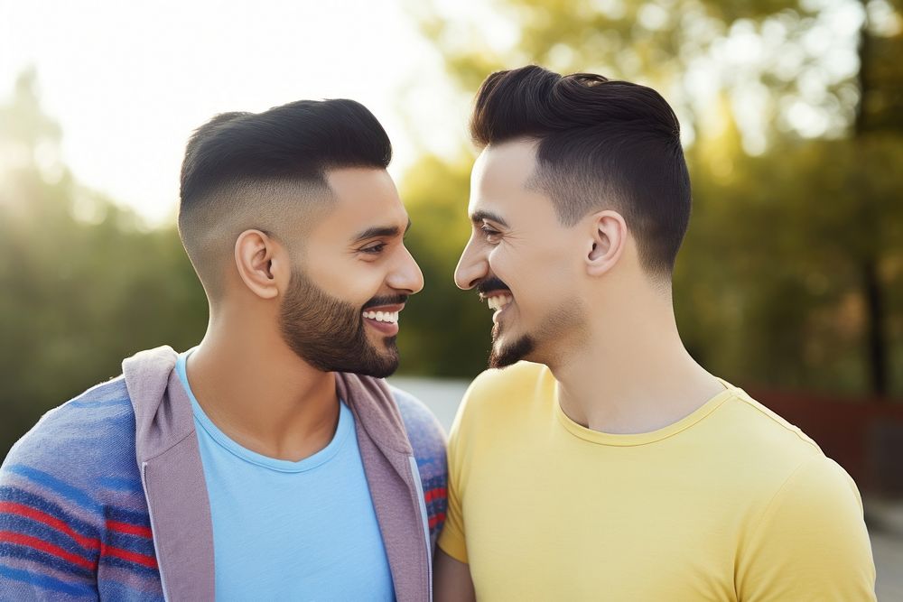 Hispanic Two happy smiling friends from lgbt community standing looking at each other together adult togetherness…