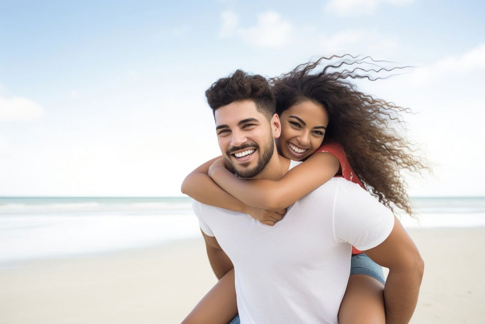 Hispanic Young Couple On Beach Summer Vacation Happy Smiling Man Carry Woman Back Seaside laughing vacation smiling. AI…