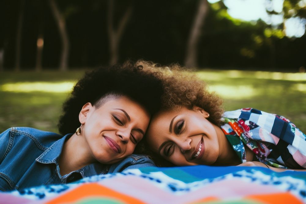 Hispanic Happy loving lesbian LGBT couple lie on the bedspread in the park photography portrait blanket. AI generated Image…