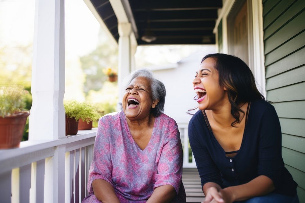 Latinx Senior woman and adult daughter laughing on porch togetherness architecture retirement. AI generated Image by…