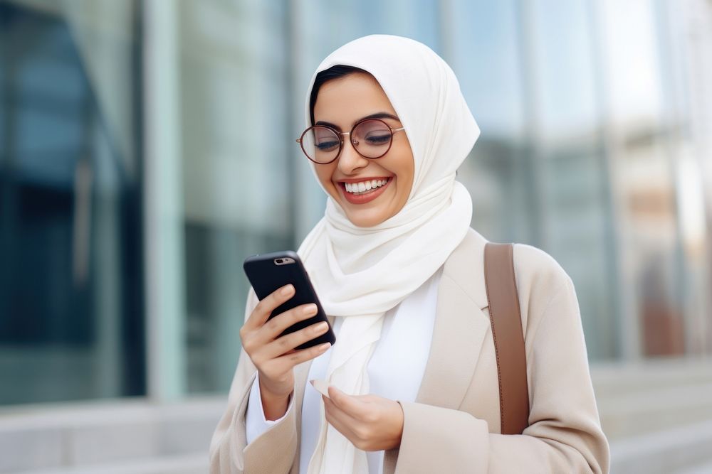 Arab woman using mobile phone smiling scarf city. AI generated Image by rawpixel.