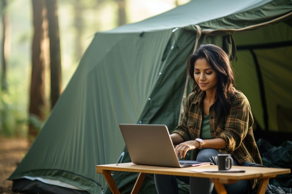 Indonesian woman with laptop in front of tent camping computer outdoors. AI generated Image by rawpixel.