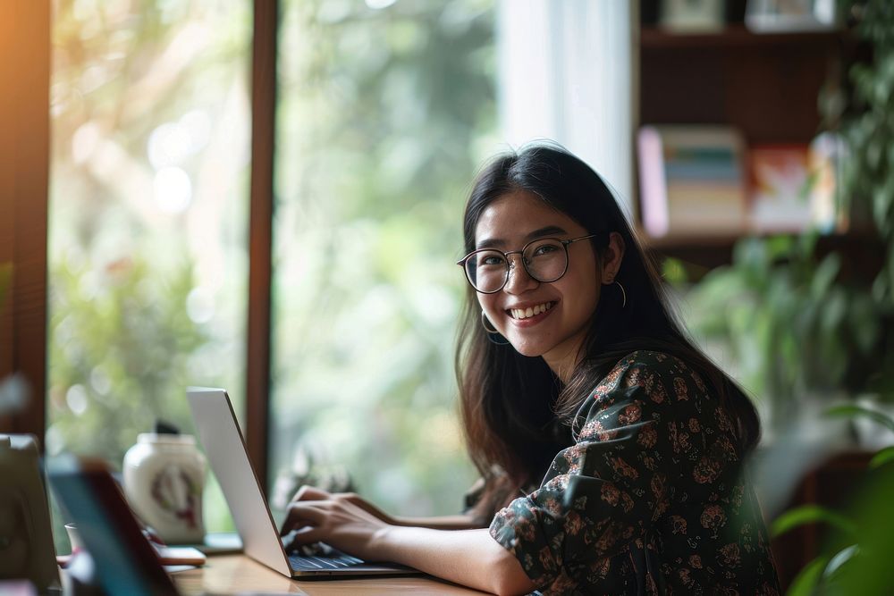 A smiling girl doing work at home laptop computer sitting. AI generated Image by rawpixel.