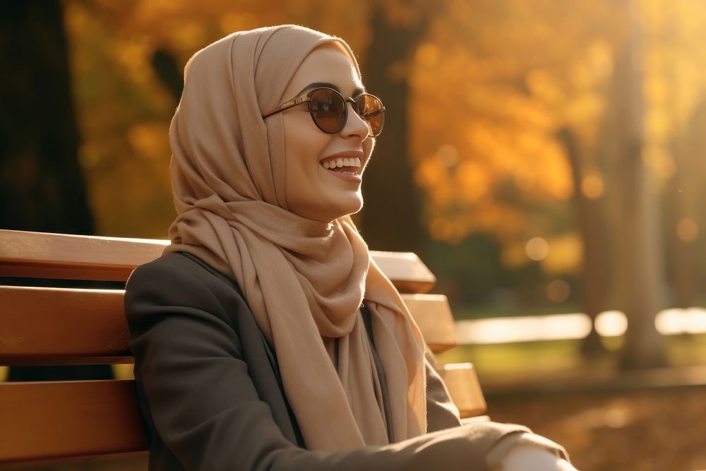 Women in hijab laughing on a bench in the park smile sitting adult. 