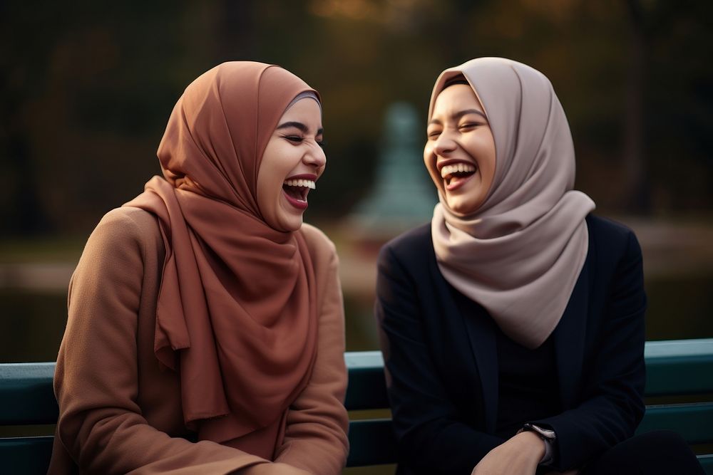 Women in hijab laughing on a bench in the park adult smile togetherness. AI generated Image by rawpixel.