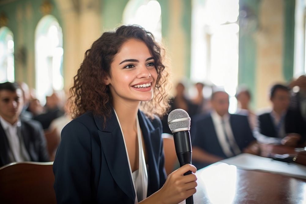 Young Cuban woman speaker with wireless microphone in business meeting audience smiling adult. AI generated Image by…
