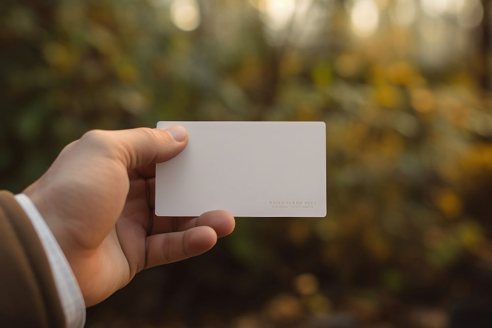 Hand holding business card electronics outdoors autumn. AI generated Image by rawpixel.