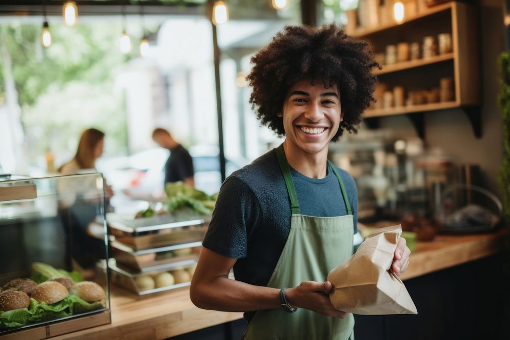 A multiracial teen man wearing green linen apron organic holding adult. AI generated Image by rawpixel.