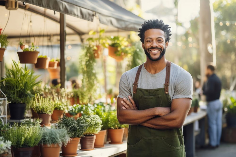 A multiracial man holding a potted plants in front of plant shop outdoors working market. AI generated Image by rawpixel.