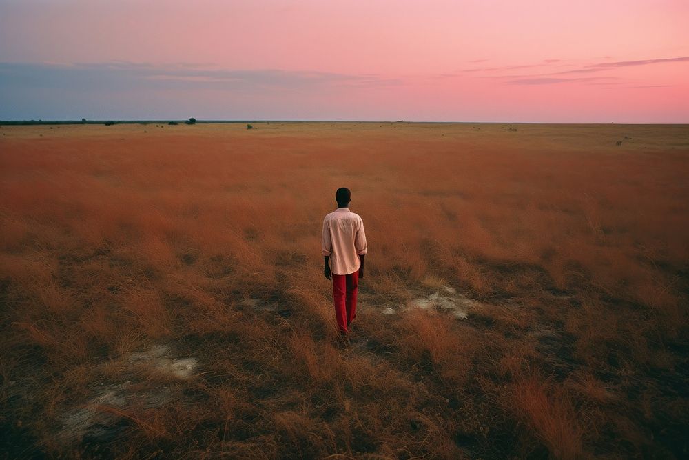 An happy affrican man standing in a minimal-large grassland landscape outdoors horizon. AI generated Image by rawpixel.