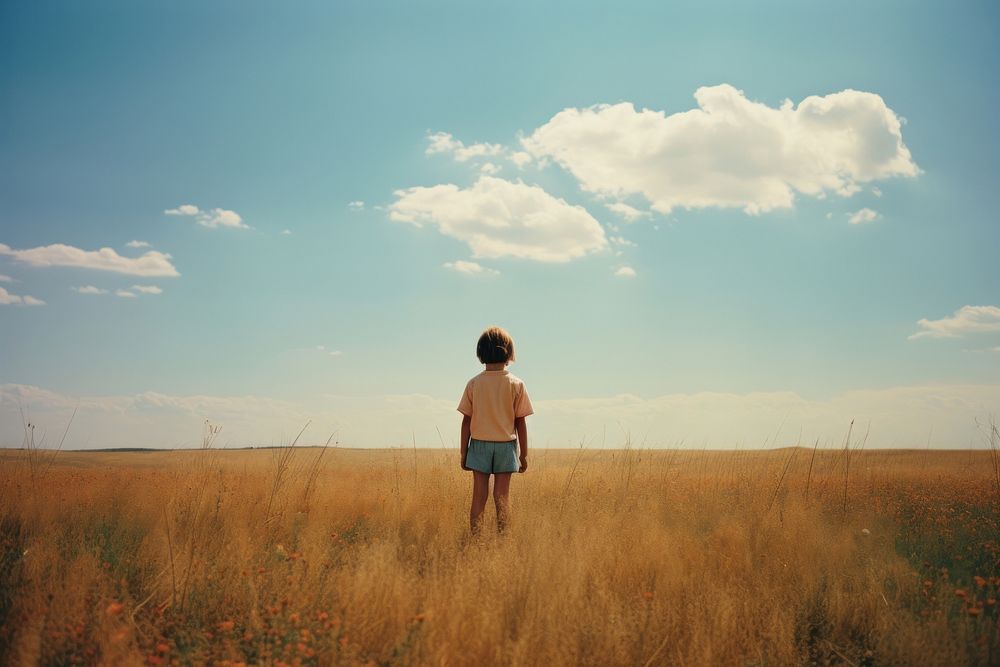 An happy child standing in a minimal-large grassland landscape photography outdoors. AI generated Image by rawpixel.