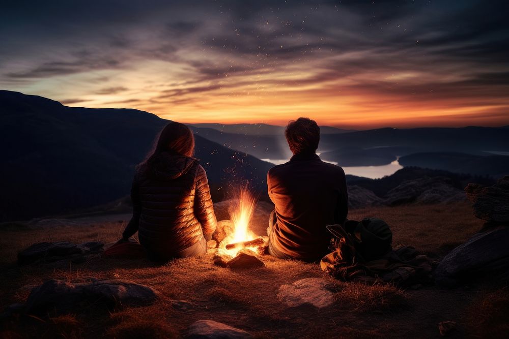 A couple sitting by the campfire outdoors camping bonfire. AI generated Image by rawpixel.