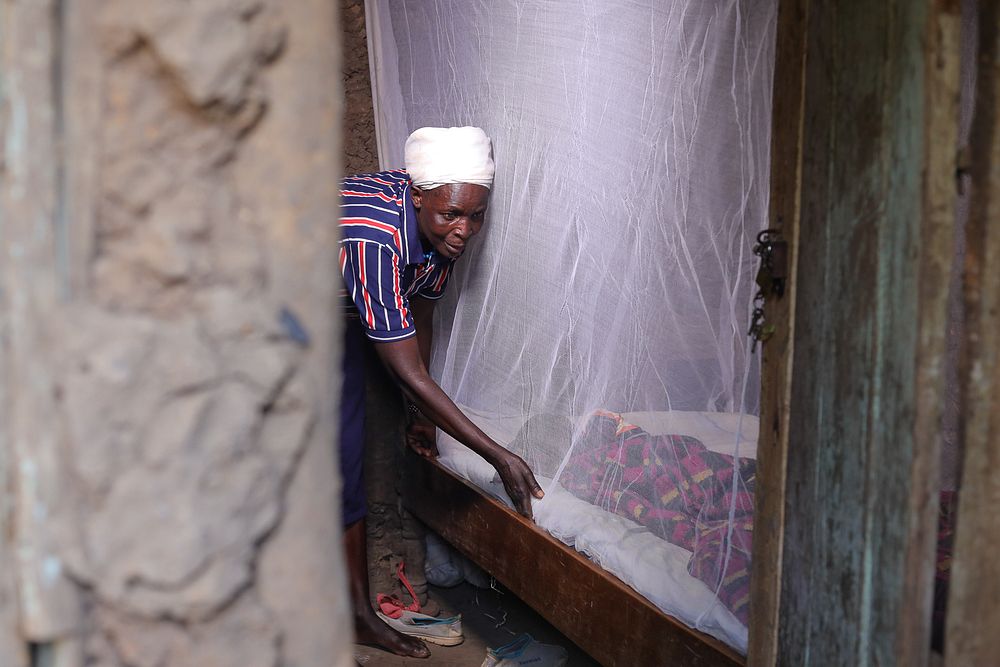A woman sets up her new mosquito net to protect her sleeping child from malaria.
