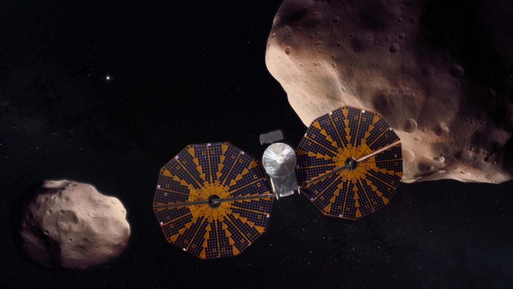 This artist’s concept depicts the Lucy spacecraft flying past the Trojan asteroid (617) Patroclus and its binary companion…