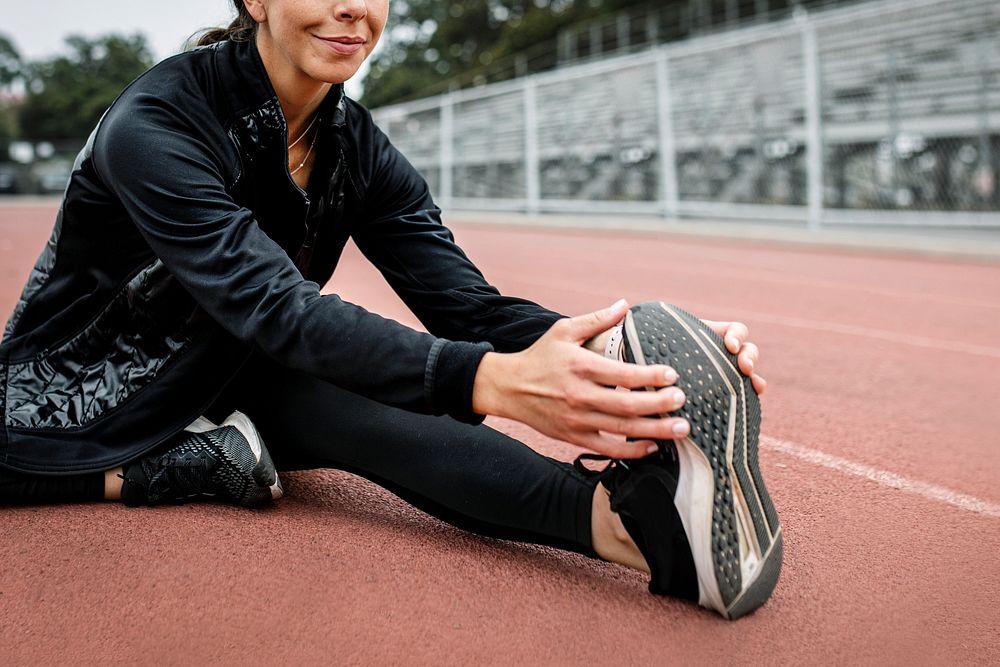 Woman warming up by stretching on a running track 