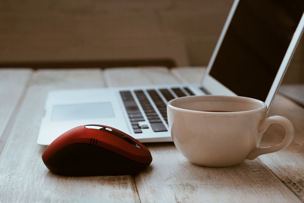 Free red computer mouse rests near a cup of coffee and a laptop computer image, public domain CC0 photo.