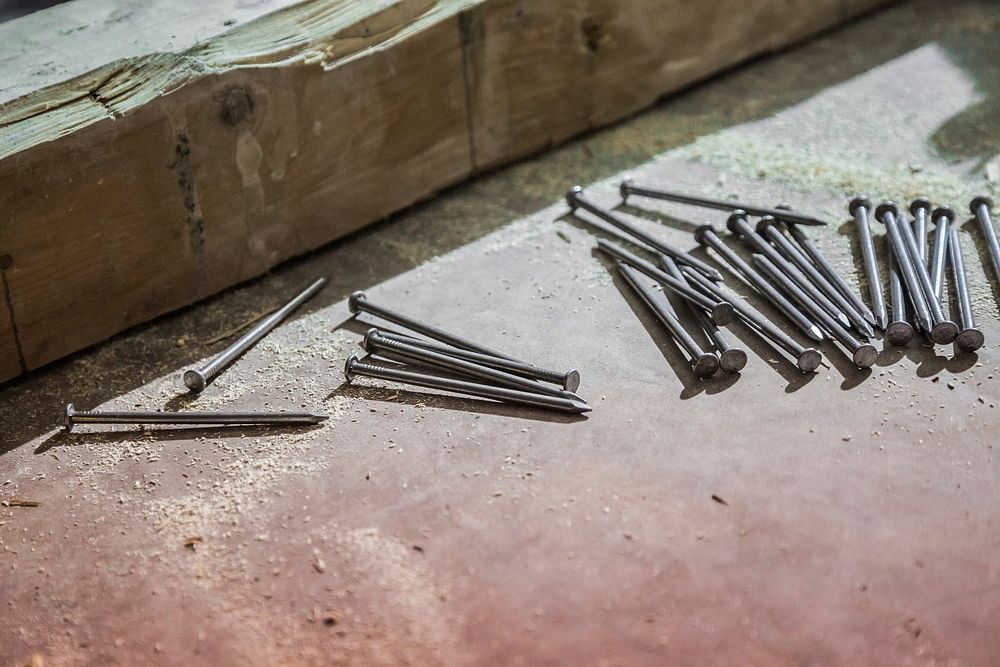 Nails and sawdust rest beside a wood beam on a construction site, free public domain CC0 image.