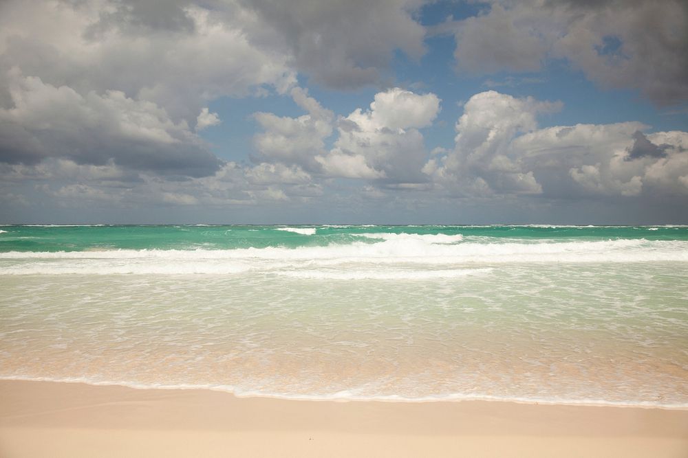 Free waves crashing on a sandy beach under blue sky public domain CC0 photo.