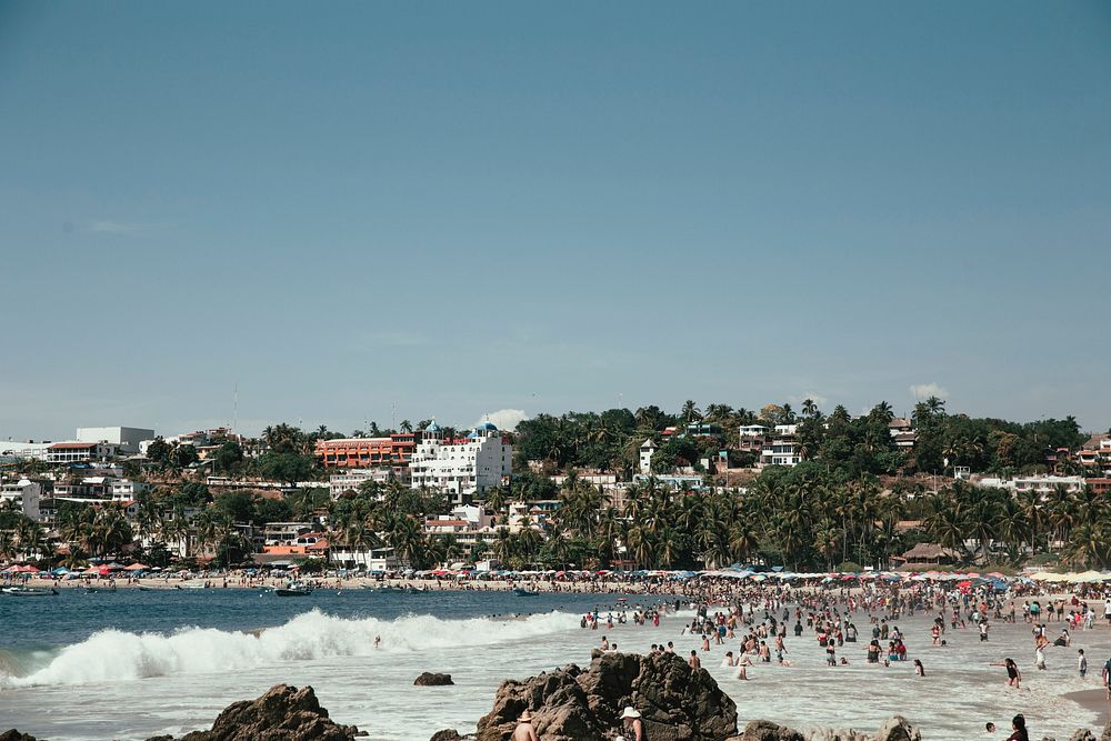 Free crowded urban beach, clear blue sky public domain CC0 photo.