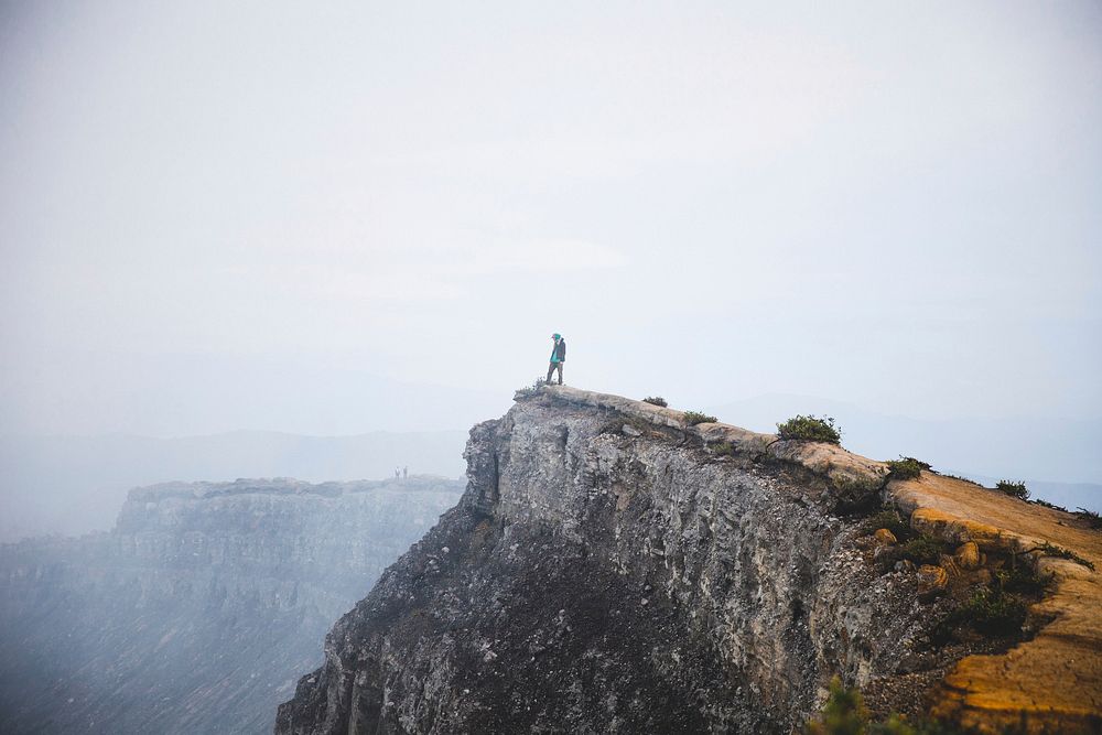 Free man standing on cliff image, public domain adventure CC0 photo.