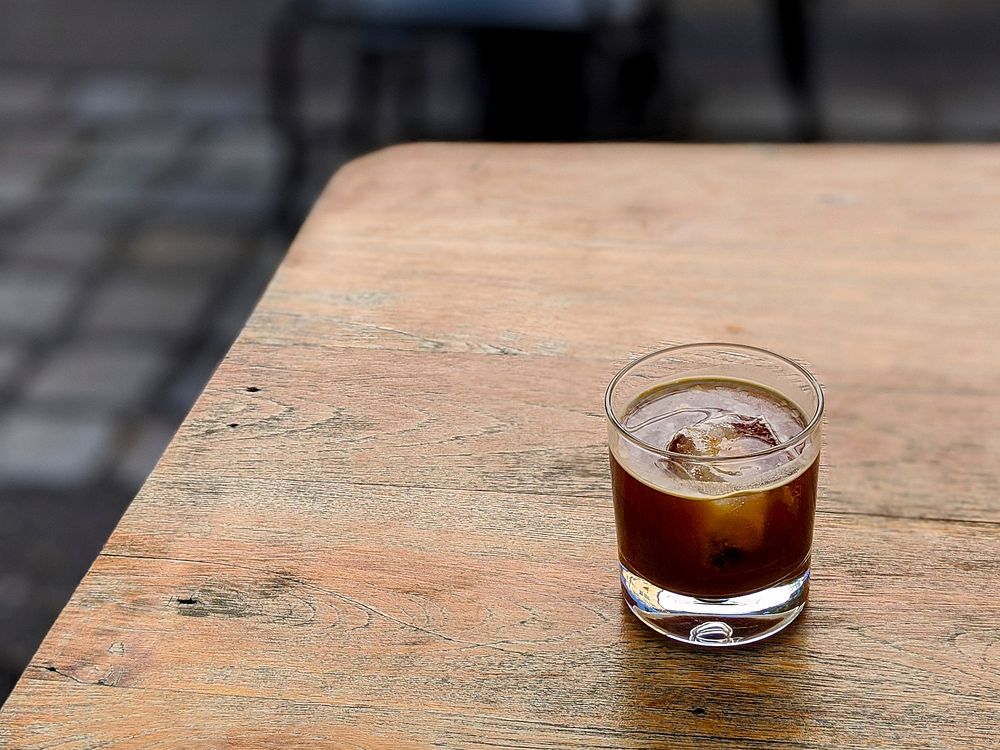 Free cold Americano coffee with ice cube on a wooden table photo, public domain beverage CC0 image.
