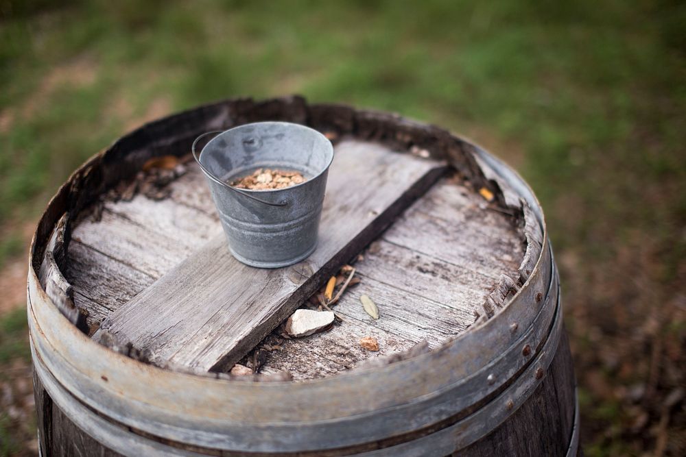Small bucket on wooden barrel. Free public domain CC0 photo.