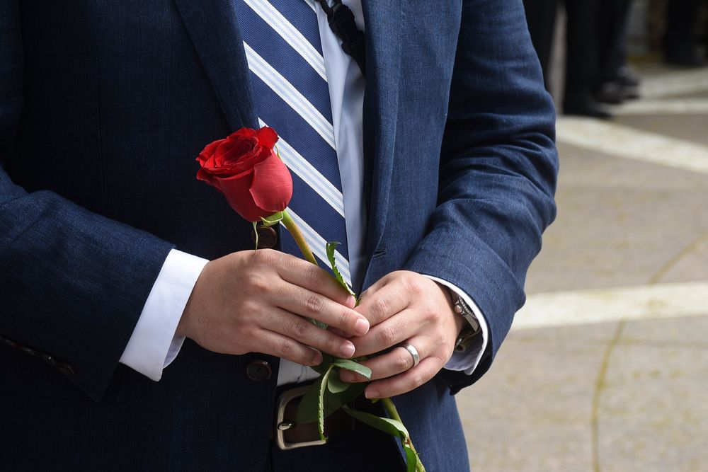 Man holding a red rose at the ICE Valor Memorial and Wreath Laying Ceremony. Original public domain image from Flickr