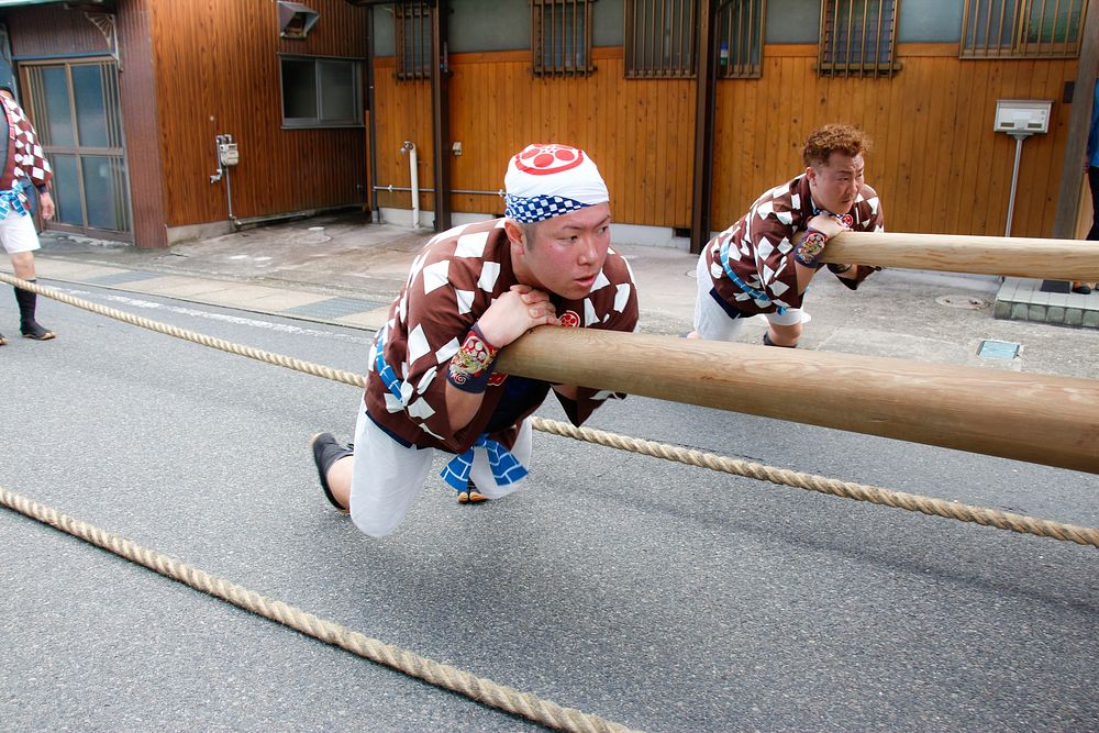 Japanese men pushing wooden poles, Japan, April 11, 2015. Original public domain image from Flickr