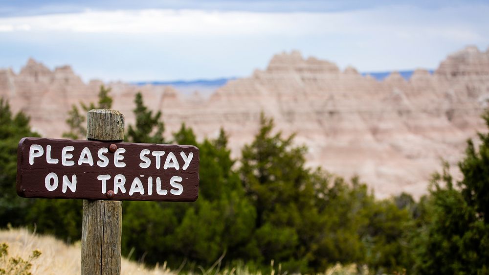 Please stay on trails sign on Badlands National Park in October. NPS Photo/M.Reed. Original public domain image from Flickr