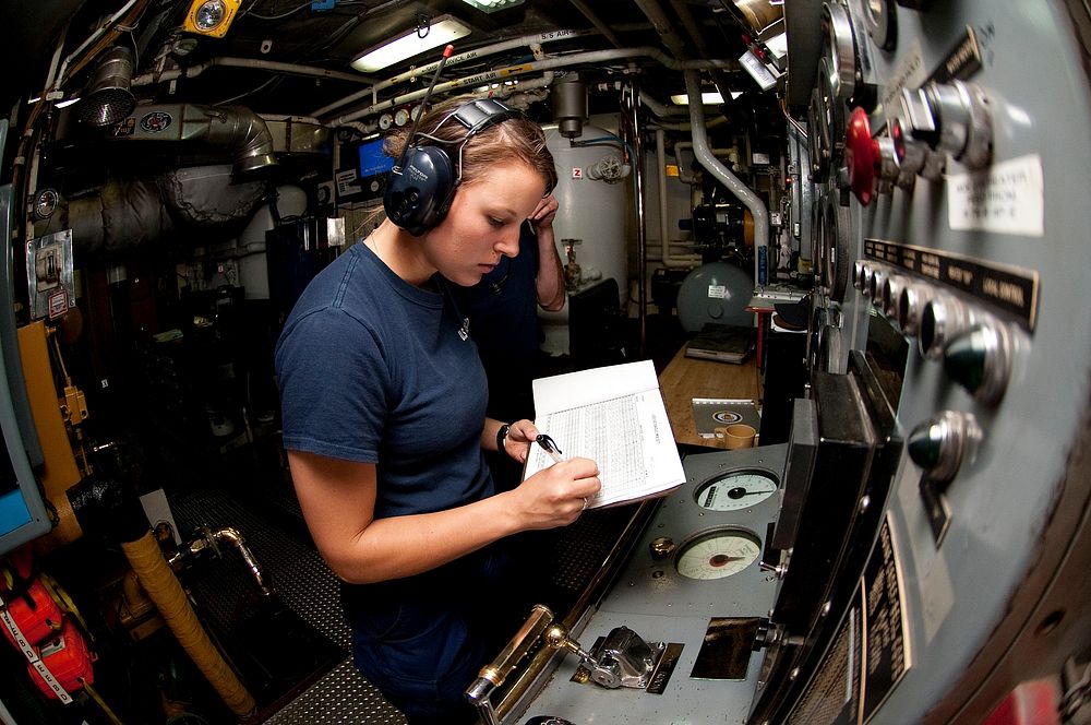 U.S. Coast Guard First Class Cadet Holly Madden logs a reading in the engine room aboard the Coast Guard Cutter Eagle…
