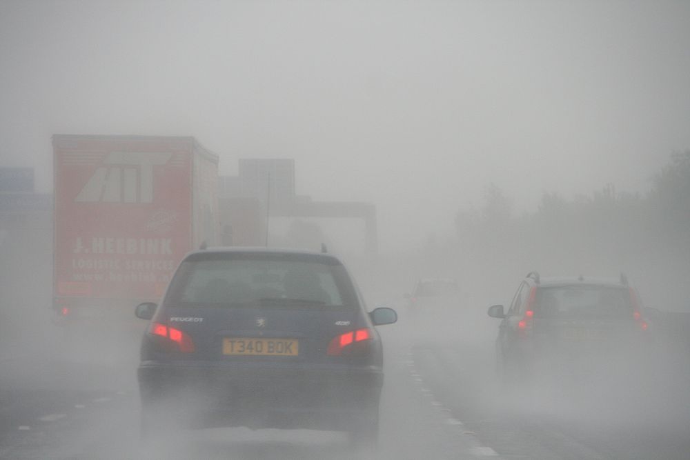 Cars driving on a busy road in fog. Original public domain image from Flickr