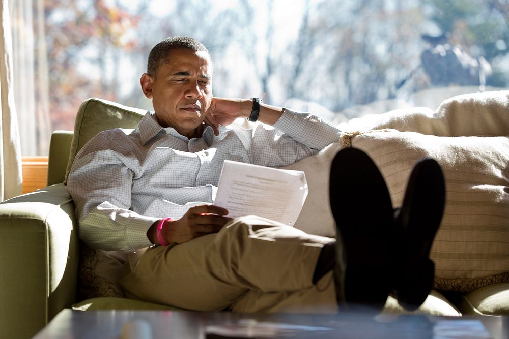 President Barack Obama reads briefing material while meeting with advisors inside his cabin at Camp David, Sunday, Oct. 21…