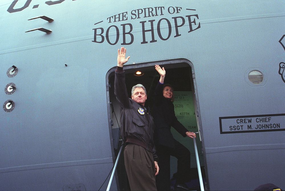 The Clintons wave from the doorway of The Spirit of Bob Hope airplane on departing from Sarajevo en route to Tuzla