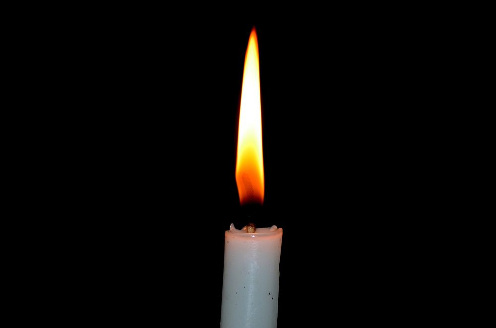 Burning candle in the dark. Free public domain CC0 image.