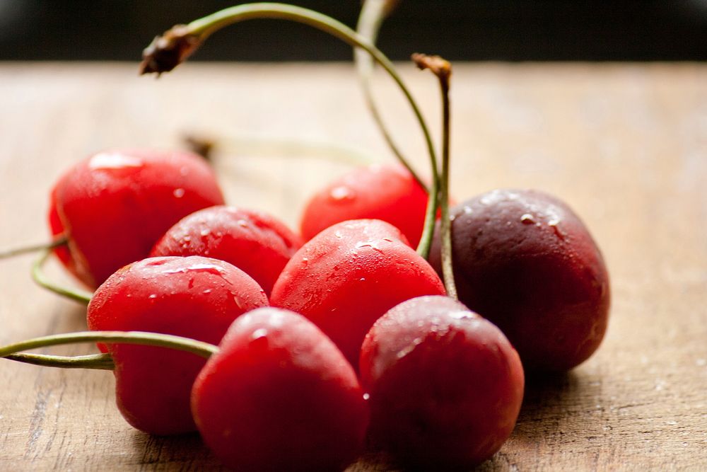 Closeup on fresh cherries on wooden table. Free public domain CC0 image.