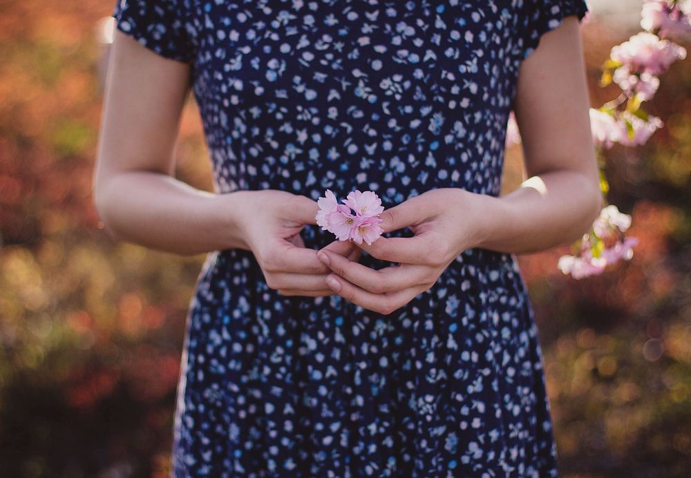 Free woman in dress holding flower on a field photo, public domain CC0 image.