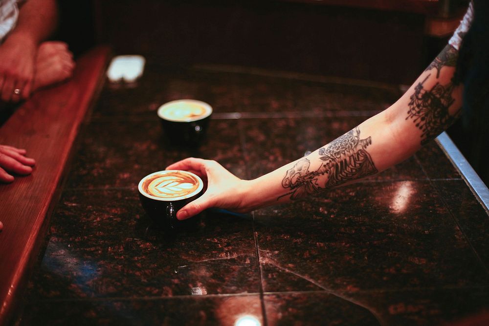 Free tattoo hand holding coffee cup photo, public domain beverage CC0 image.