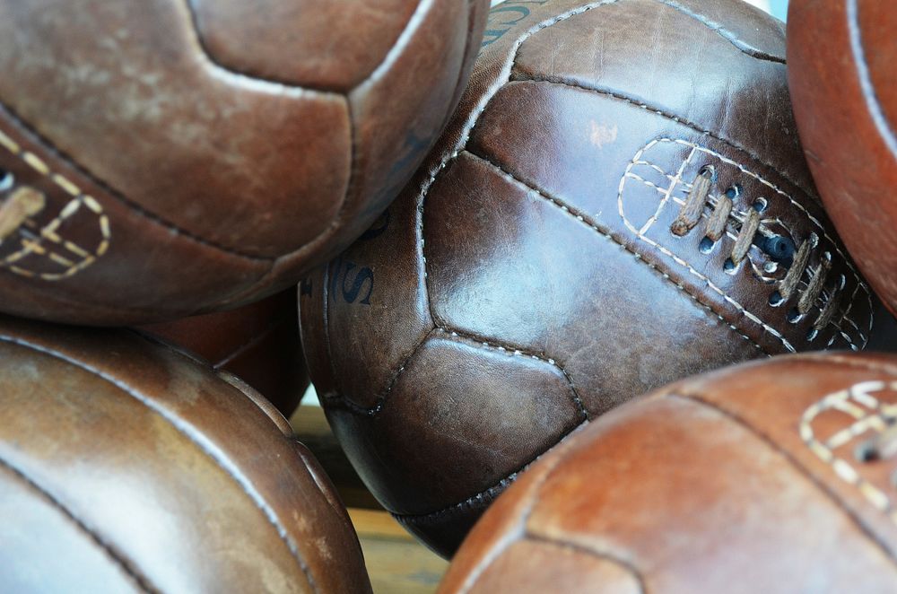 Closeup on pile of vintage old footballs. Free public domain CC0 photo.