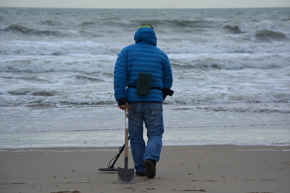 Man with metal detector at the beach. Free public domain CC0 photo.