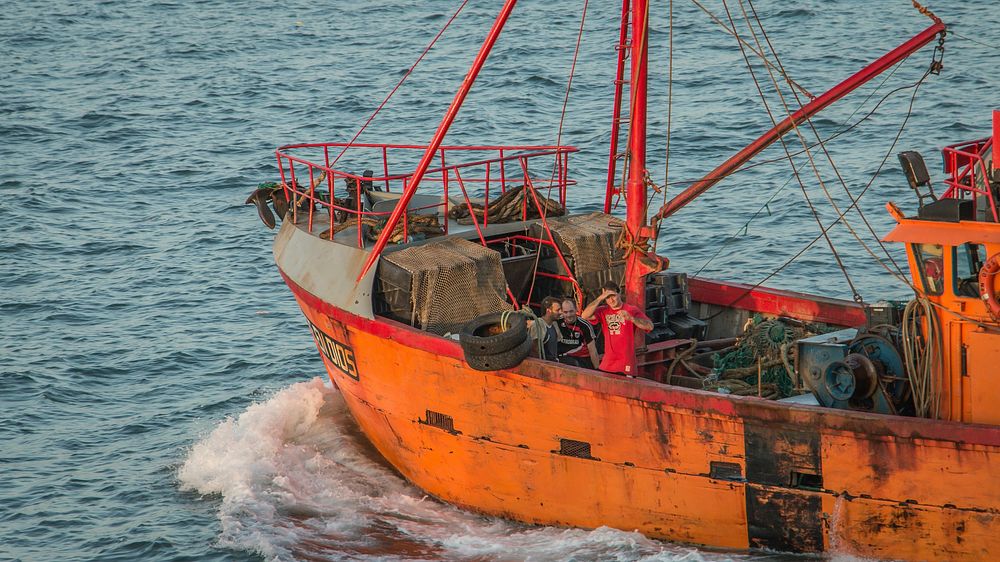 Old orange fishing boat sailing. Free public domain CC0 photo.