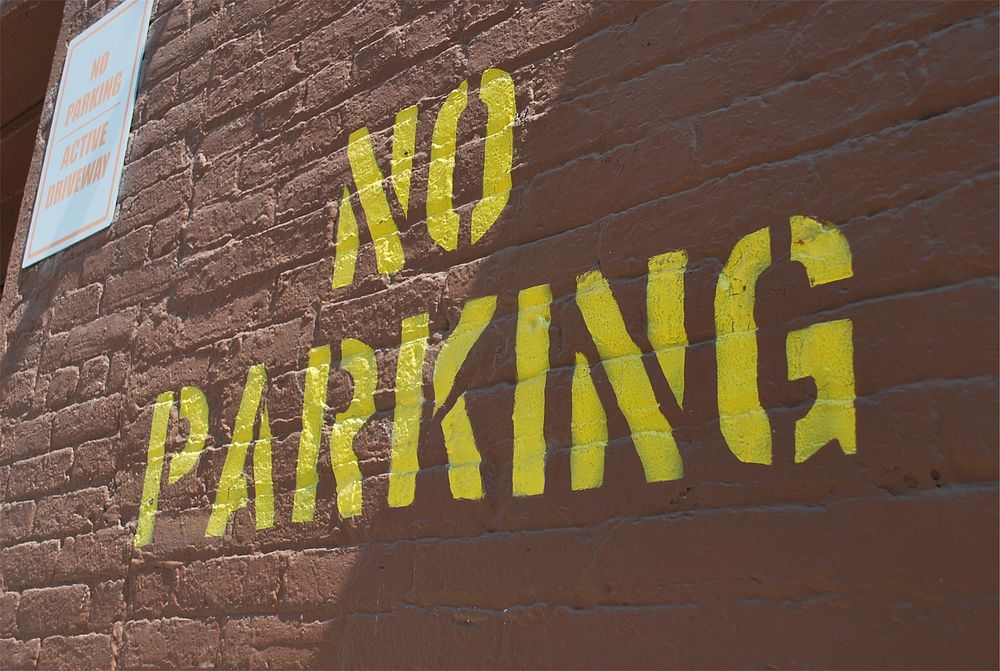 No parking sign on brick wall. Free public domain CC0 image.