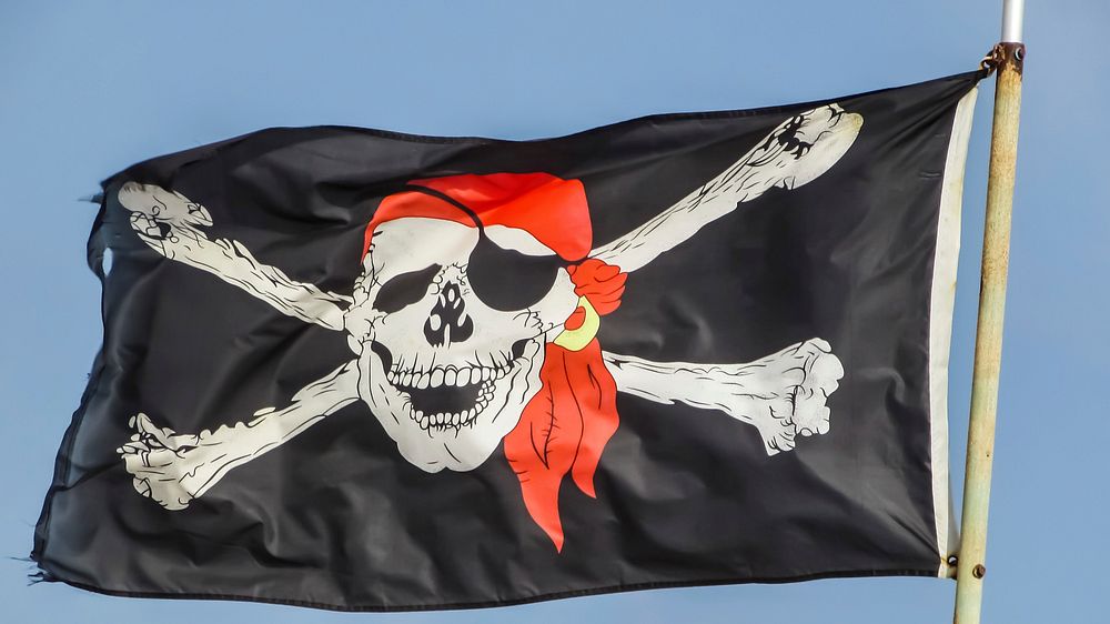 Pirate flag against blue sky, free public domain CC0 photo.