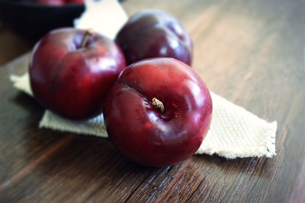 Closeup on fresh plums on wooden table. Free public domain CC0 photo.