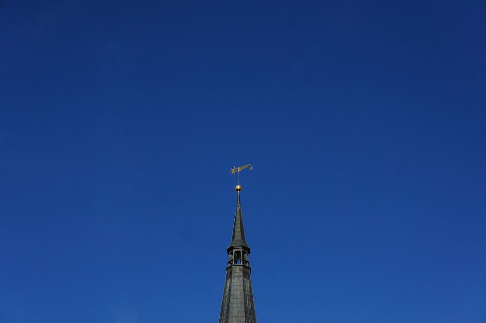 Building steeple with a flag weather vane. Free public domain CC0 image.