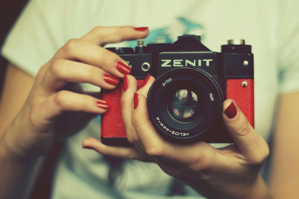 Woman holding Zenit retro camera, location unknown, date unknown.