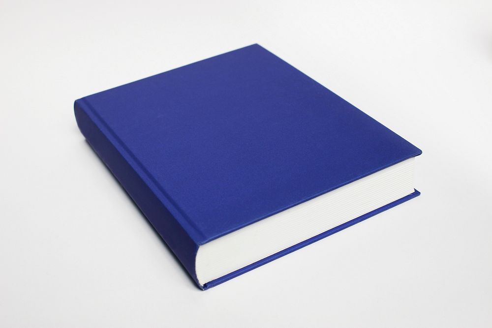Free closed blue book on white table photo, public domain CC0 image.