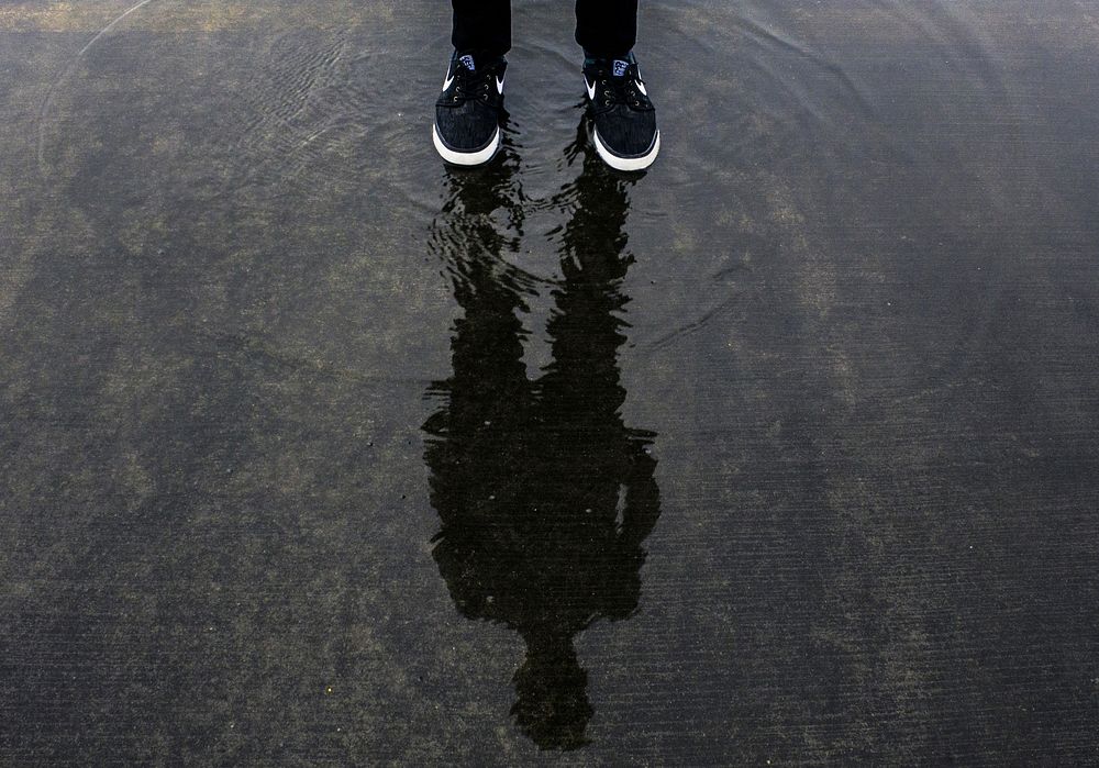 Free person standing on wet ground with black sneakers image, public domain shoes CC0 photo.